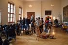 Účastníci workshopu poslouchají výklad ke středověkým střihům oblečení. 